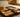 Open suitcase on a hotel bed packed with clothing and a small discreet lipstick-style vibrator among the items.