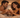 A warm, intimate photograph of an adult couple lying in bed, smiling at each other and sharing a quiet moment of connection in soft ambient light.