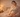 A confident postpartum mother stands in a warmly lit bedroom, smiling and feeling at ease in her body after childbirth.