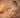 A confident postpartum mother stands in a warmly lit bedroom, smiling and feeling at ease in her body after childbirth.