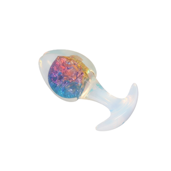 Transparent anal plug with crystal-like multicolor core on plain background.
